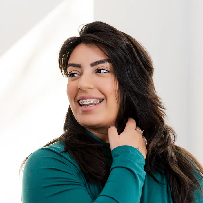 adult woman in braces looking over her shoulder and smiling