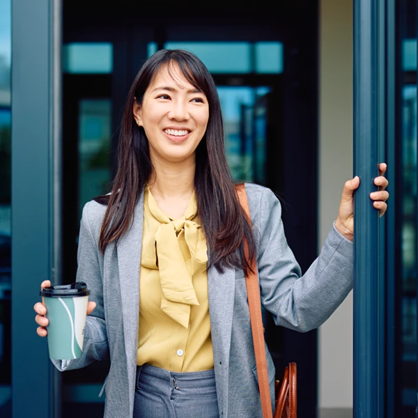 woman exiting an office building in business attire and smiling
