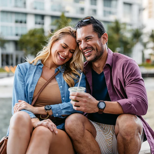 couple outdoors sitting next to a canal, laughing and smiling